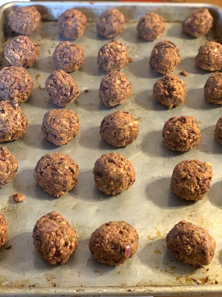 Swedish Meatballs before baking in rows on a parchment-lined baking sheet